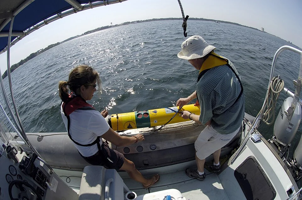 Researchers preparing to launch a yellow REMUS autonomous underwater vehicle