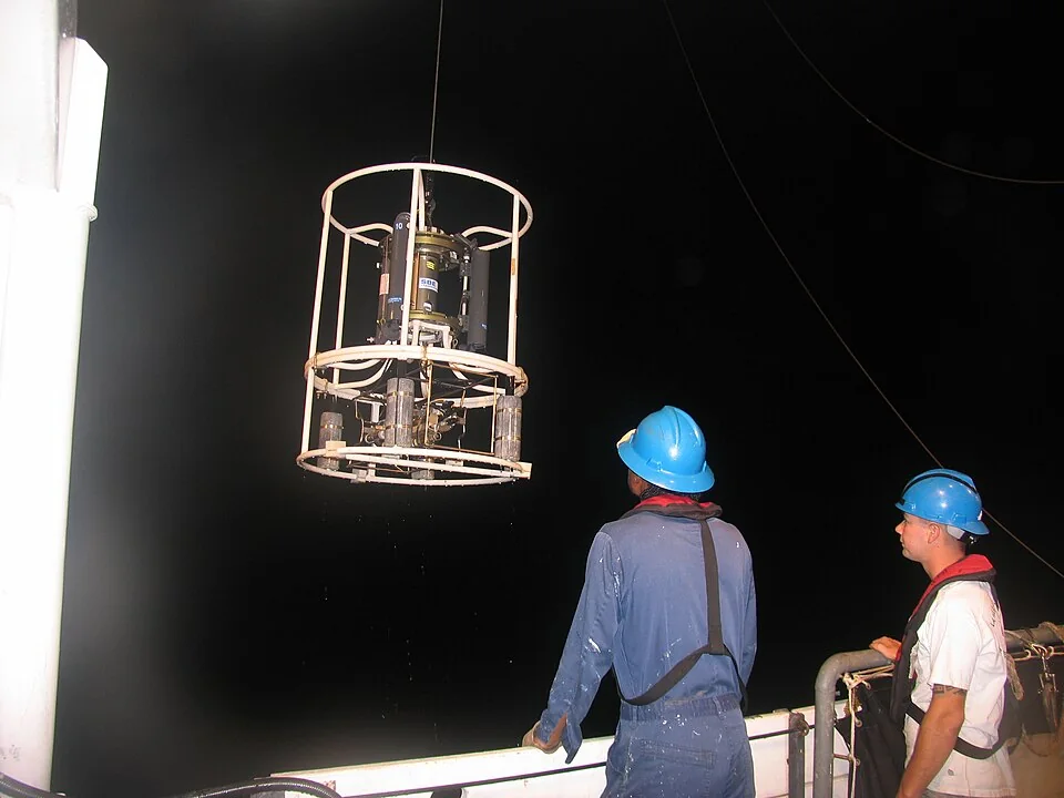 Scientists deploying oceanographic sampling equipment from a research vessel